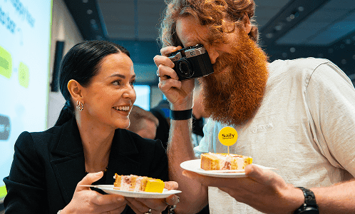 Personas tomando fotos del pastel mientras celebran el cumpleaños de Saily en la sede de la empresa eSIM.