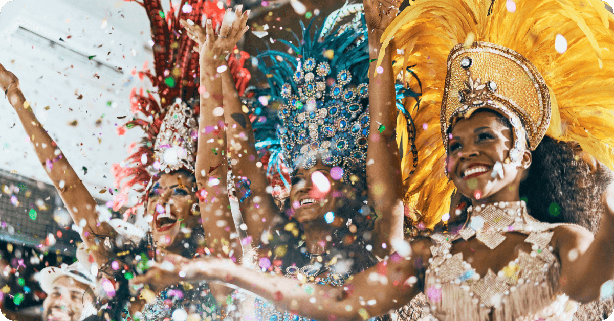 Carnival performers in Rio wearing elaborate costumes and headgear, smiling as they look ahead.