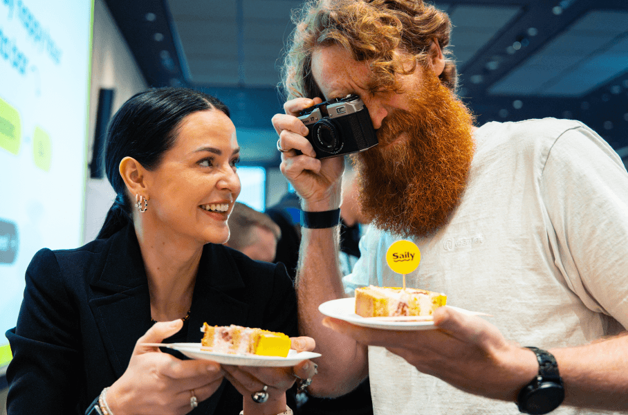 Personas tomando fotos del pastel mientras celebran el cumpleaños de Saily en la sede de la empresa eSIM.