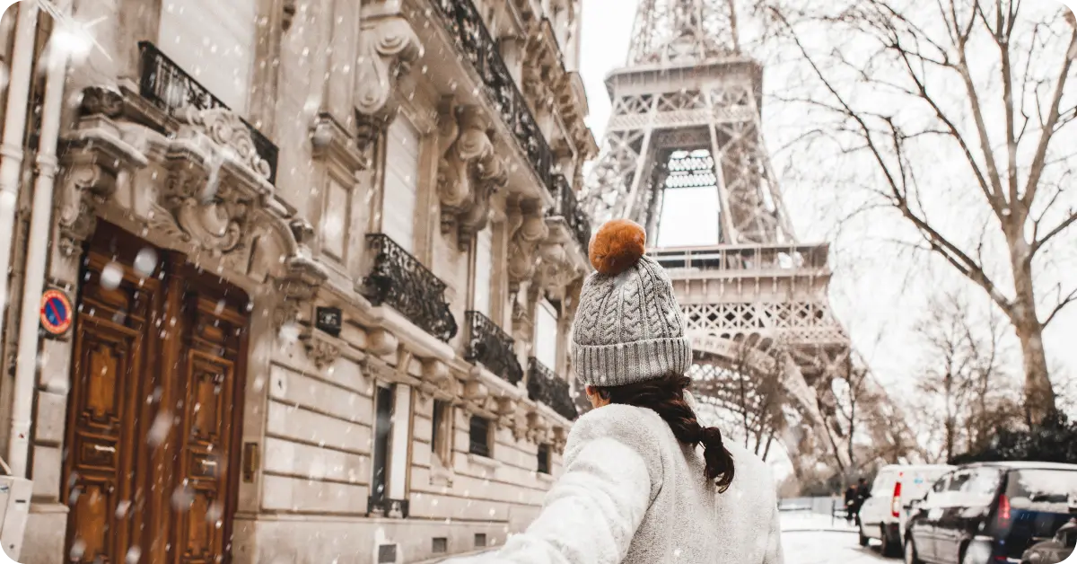 A woman near Eiffel tower in Paris with snow falling around