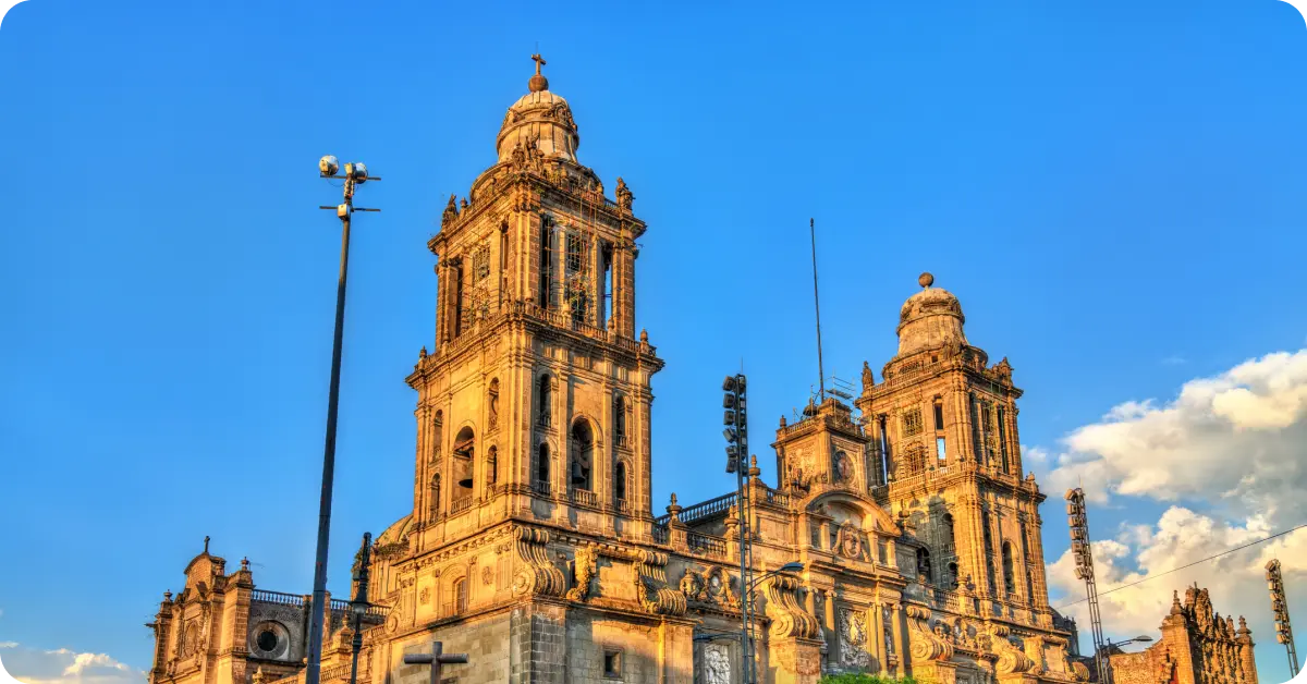 Wide shot of the Zócalo with the Metropolitan Cathedral at sunset.