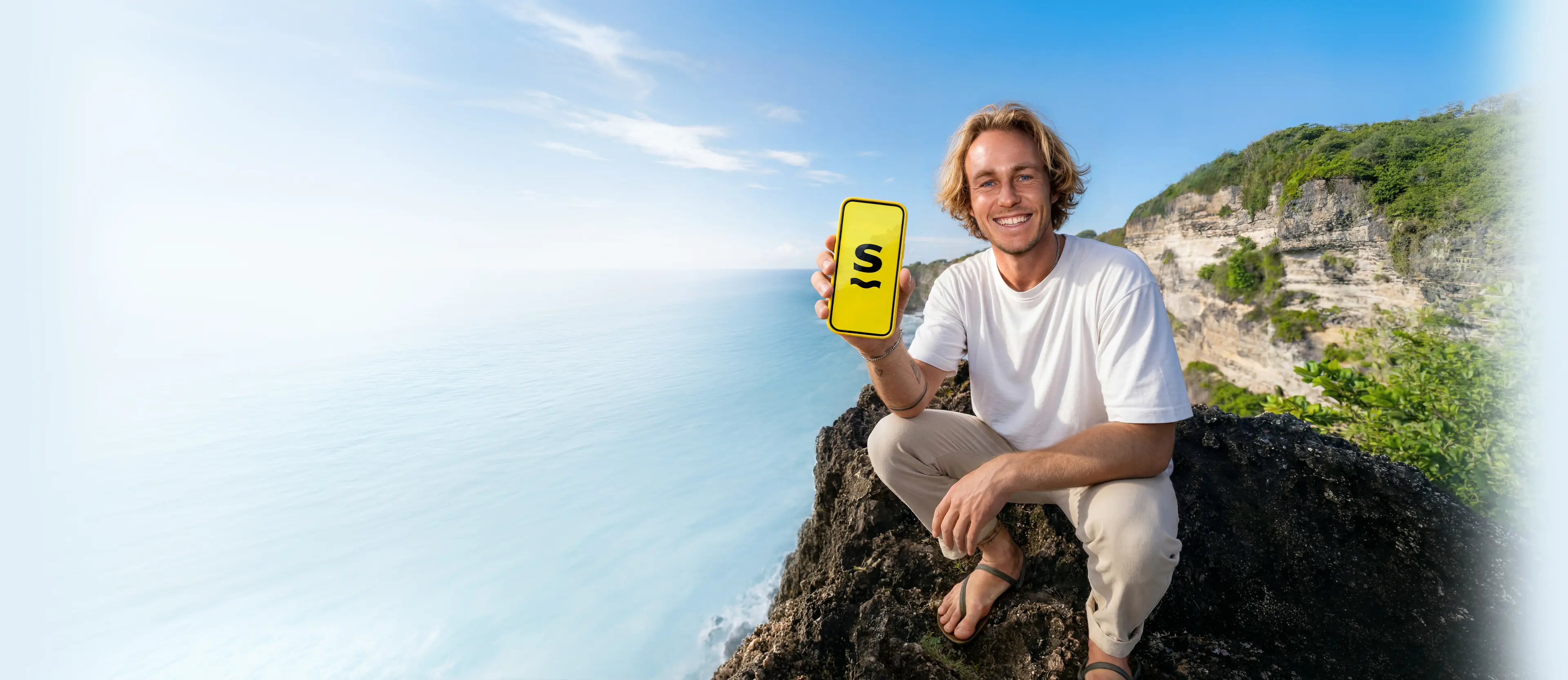 A man holding a phone with the Saily eSIM app logo on its screen.
