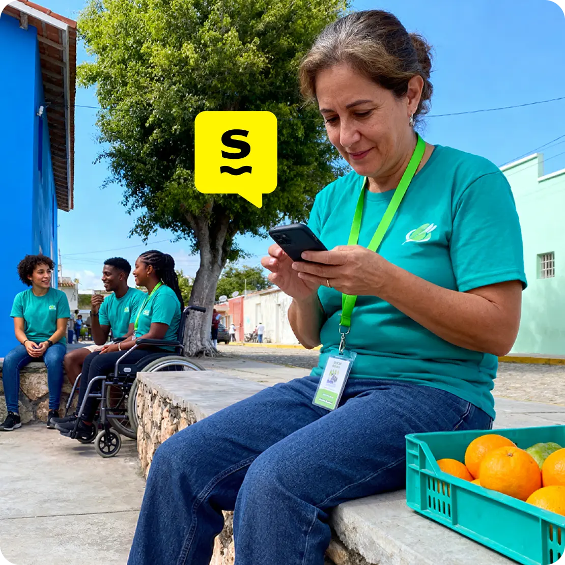 Nonprofit worker using mobile data on a smartphone during fieldwork while colleagues coordinate nearby.