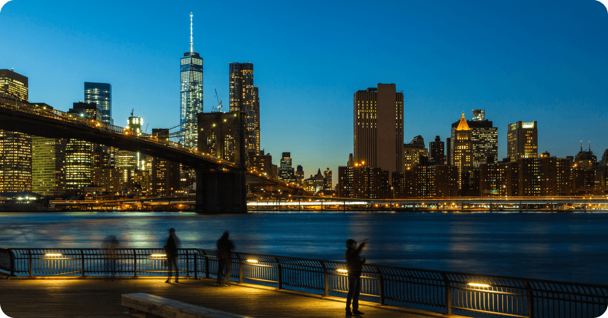 A scenic nighttime view of the Lower Manhattan skyline from a vantage point in Brooklyn