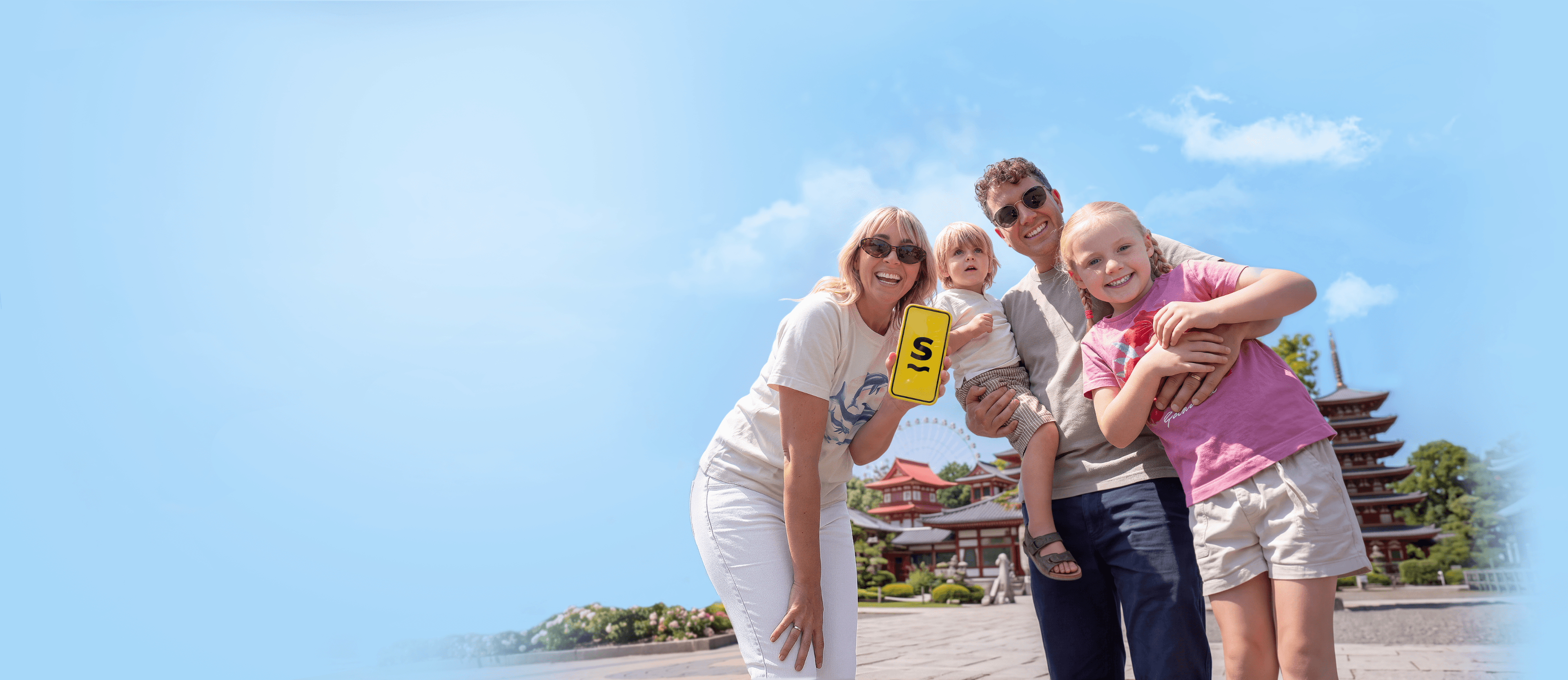 The “Flying the Nest” family holding up a phone displaying the Saily eSIM app logo.