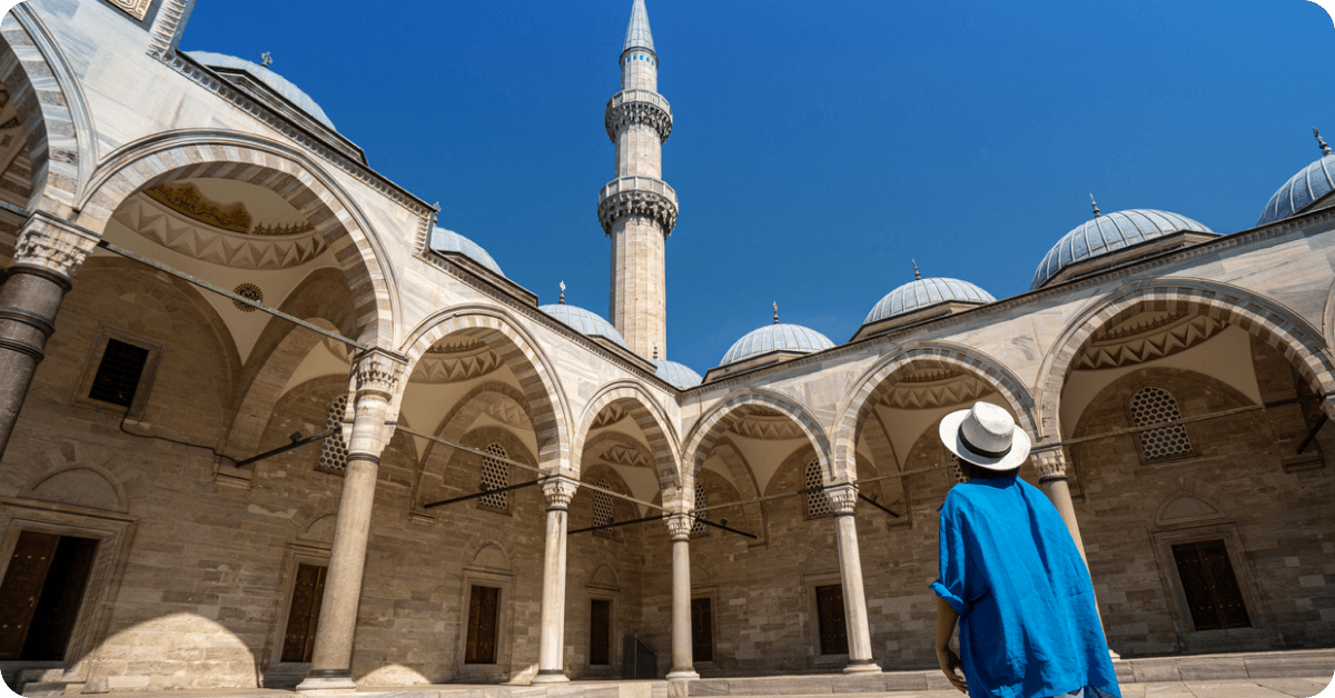 A person wearing long sleeves and a head covering outside a mosque in Turkey.