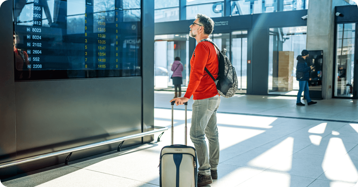 A solo traveler checks an airport departure board.