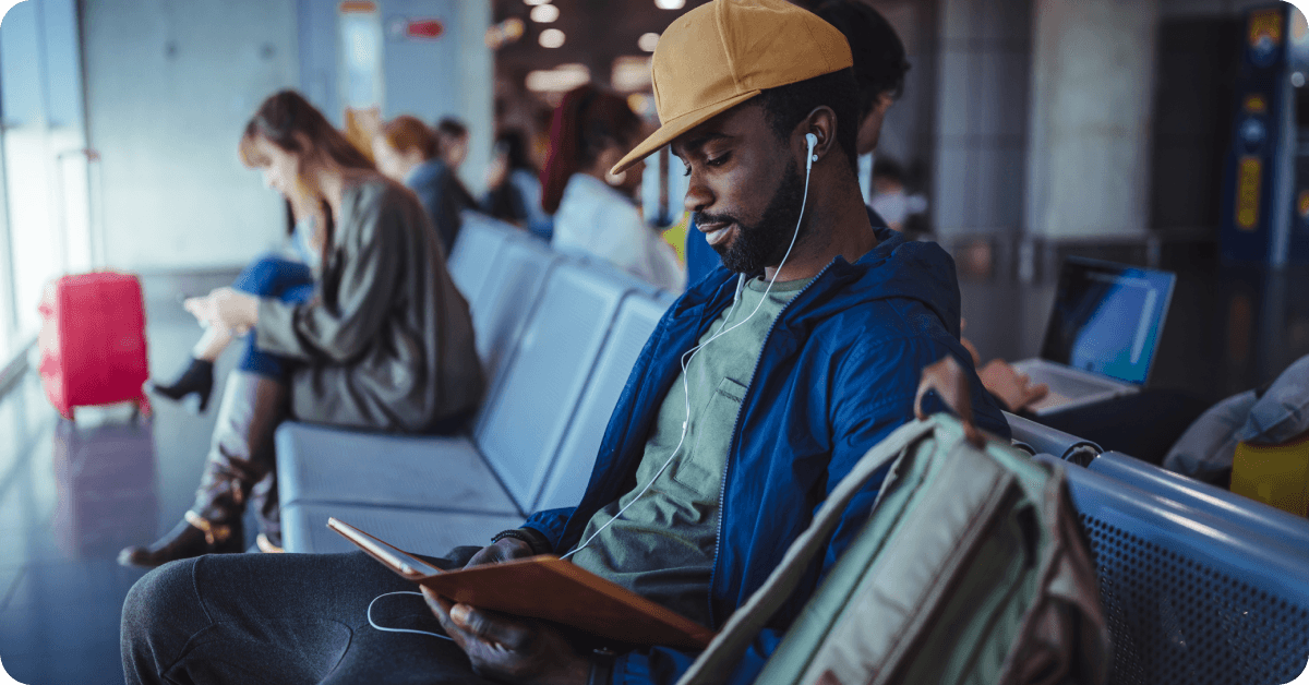 A man looks at his tablet in an airport departure lounge.