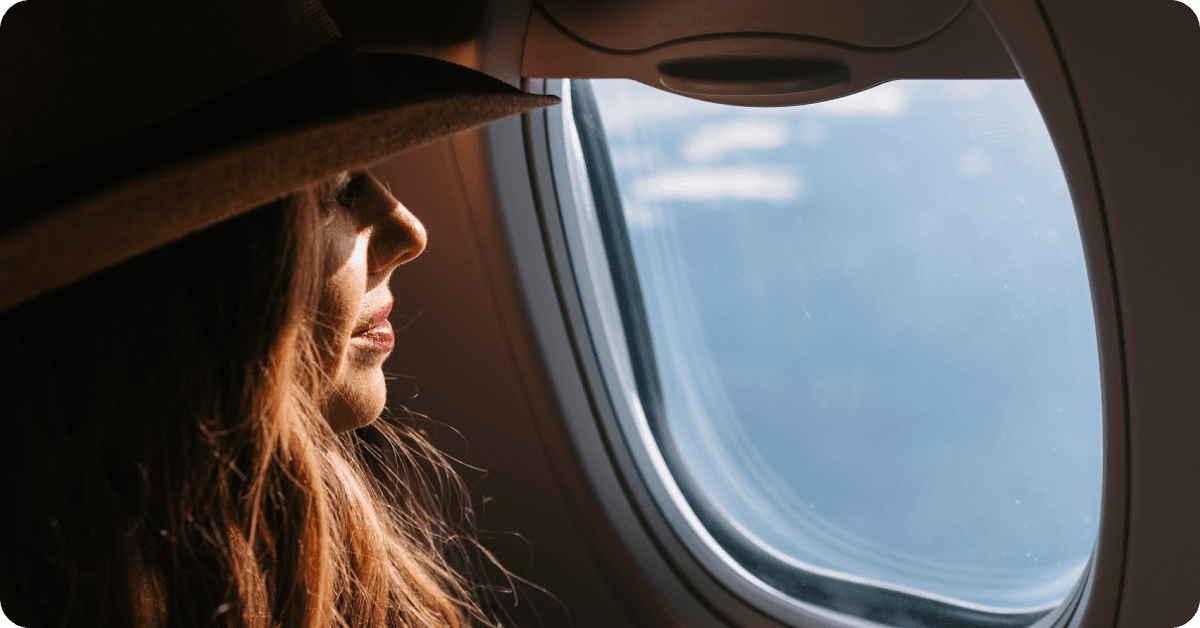 A woman looks out the plane window on her first flight.