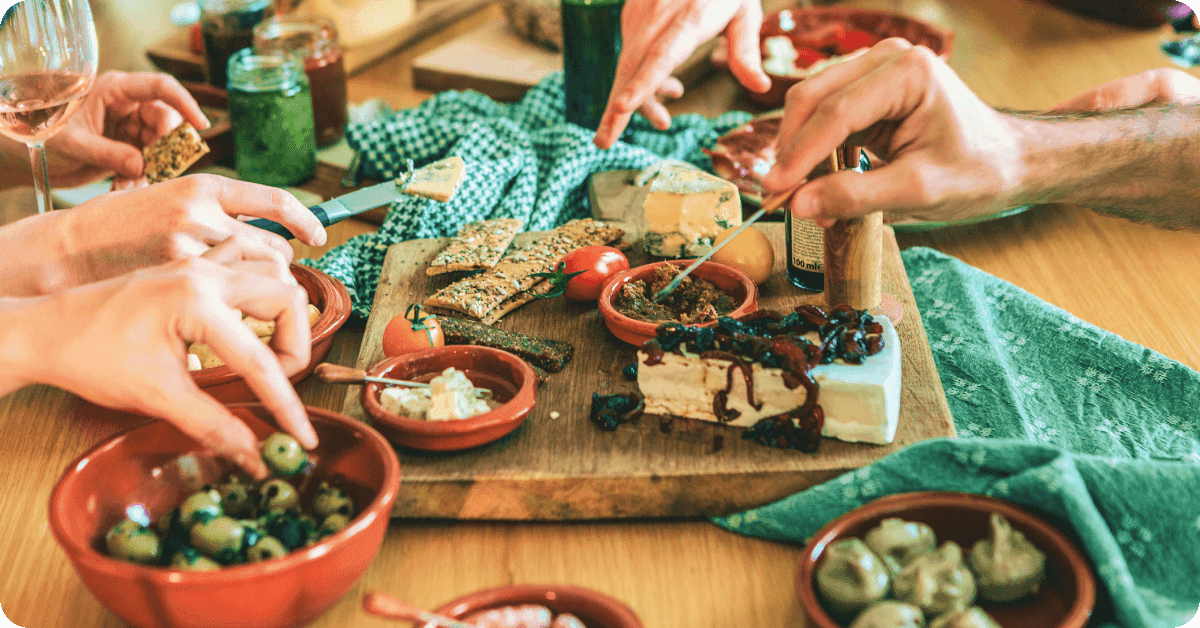 Tapas on the wooden plate and hands reaching for them