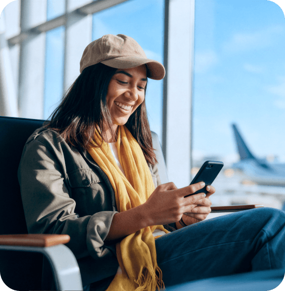 Una mujer usa su teléfono para acceder al beneficio por vuelo retrasado de Saily.