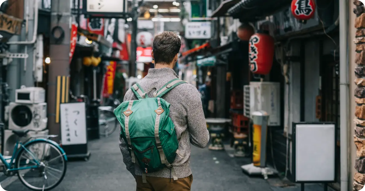 A tourist with a backpack standing in an alley in Tokyo.