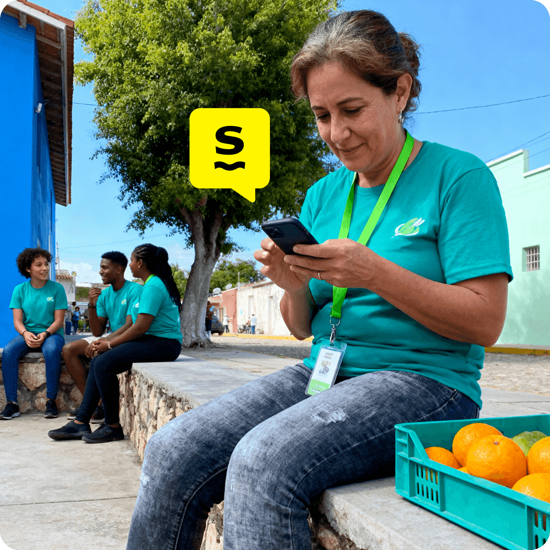 Nonprofit worker using mobile data on a smartphone during fieldwork while colleagues coordinate nearby.